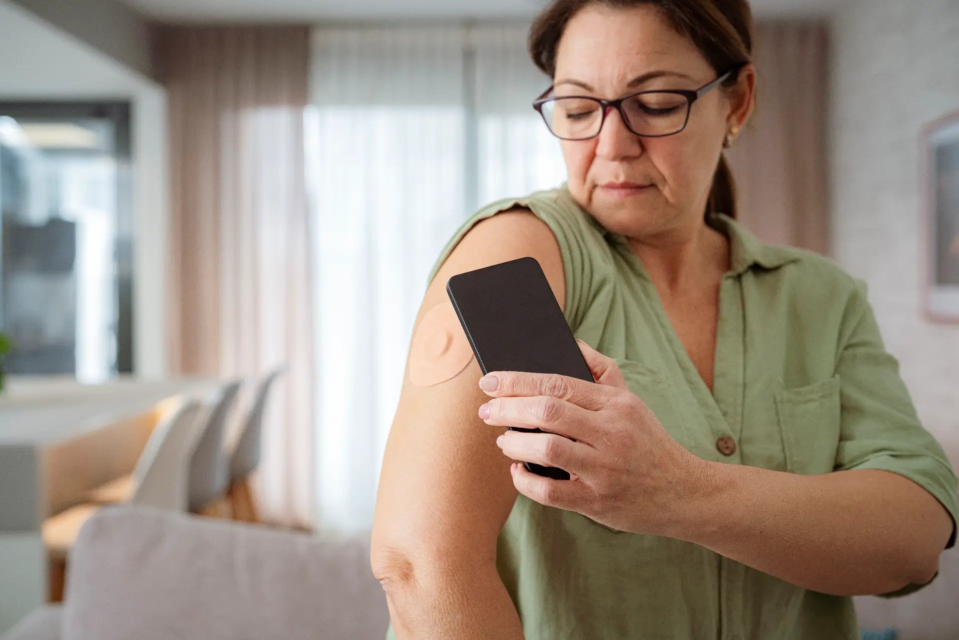 Middle-aged woman checking the CGM patch on her arm